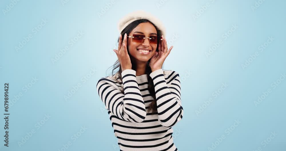 Fashion, sunglasses and woman wink in studio with trendy outfit, clothes and stylish accessories. Aesthetic, style and portrait of happy person with emoji, beauty and confidence on blue background Fashion, sunglasses and woman wink in studio with trendy outfit, clothes and stylish accessories. Aesthetic, style and portrait of happy person with emoji, beauty and confidence on blue background