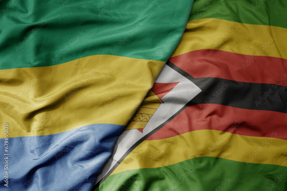 Obraz premium big waving national colorful flag of zimbabwe and national flag of gabon .