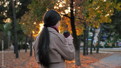 Woman sipping coffee as waiting for business meeting in town park in autumn