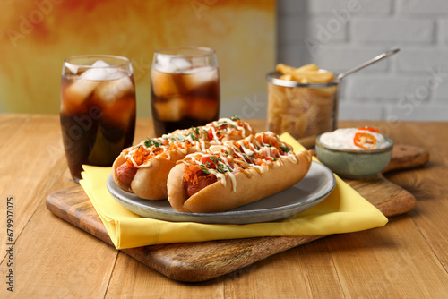 Delicious hot dogs with bacon, carrot and parsley served on wooden table