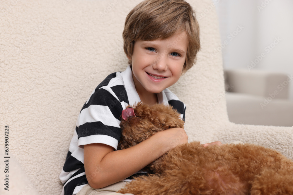 Little child with cute puppy in armchair indoors. Lovely pet Little child with cute puppy in armchair indoors. Lovely pet