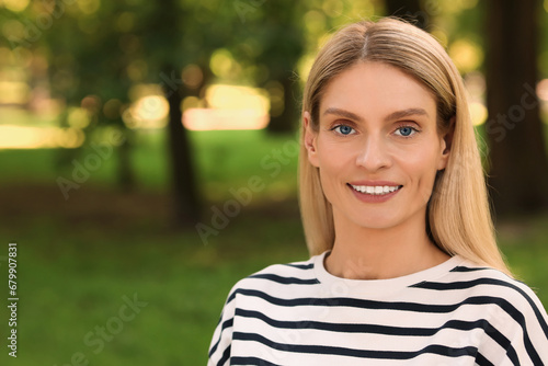 Portrait of happy woman in casual clothes outdoors. Space for text. Attractive lady smiling and posing for camera