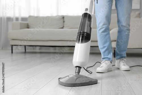 Man cleaning floor with steam mop at home, closeup. Space for text
