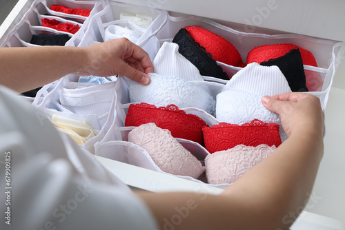 Woman putting underwear into organizer in drawer, closeup