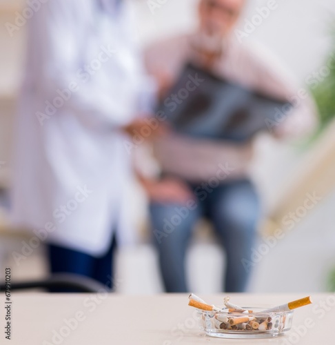 Принти на полотні Young male doctor and old patient in antismoking concept