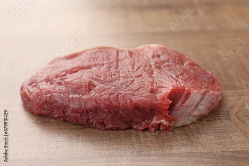 Piece of raw beef meat on wooden table, closeup
