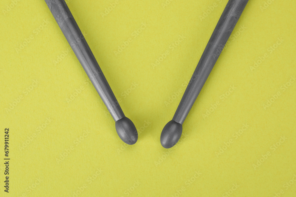 Two gray drum sticks on light green background, top view Two gray drum sticks on light green background, top view