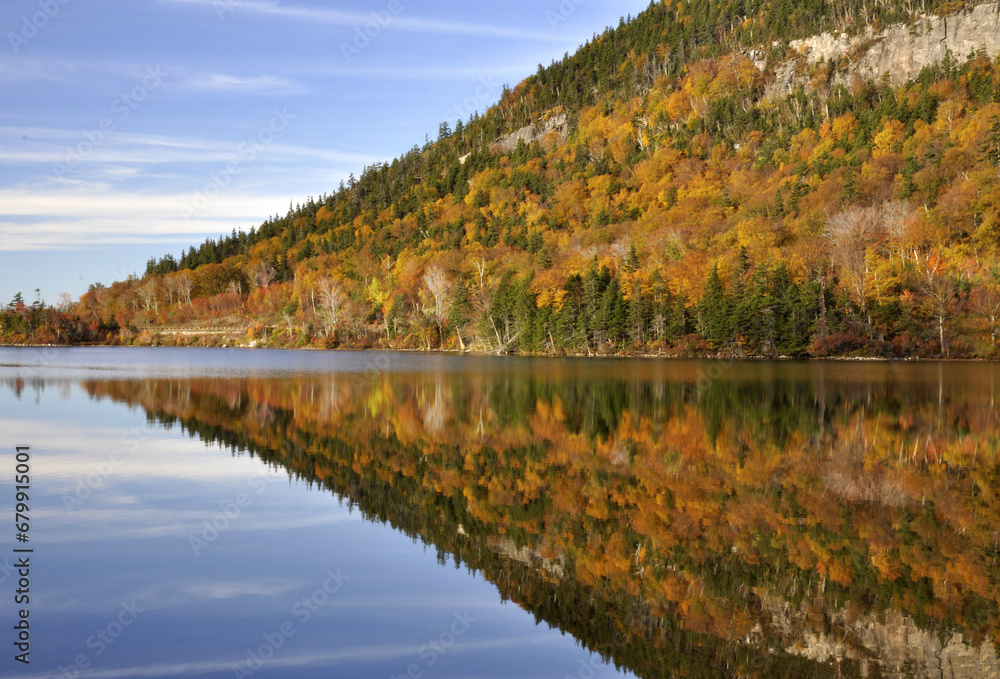 Autumn scene in Franconia Notch State Park. Colorful mirror image reflection of sky and treelined mountain on calm surface of Echo Lake in the White Mountains of New Hampshire.