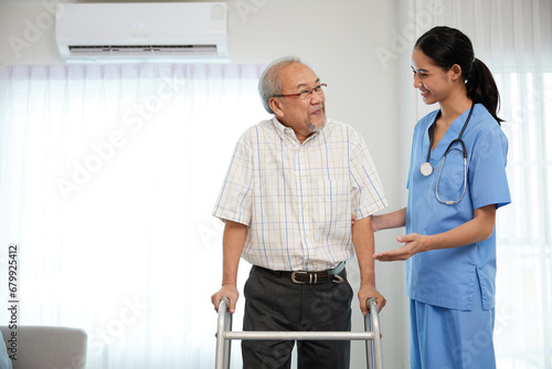 nurse or caregiver helping senior man walking with a walker and support him at home