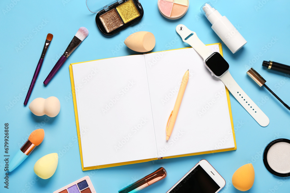 Composition with makeup cosmetics, modern mobile phone, smartwatch and notebook on blue background