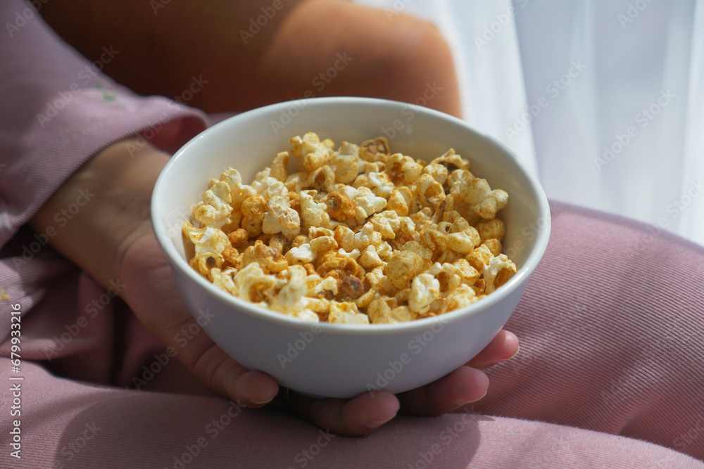 young women eating popcorn sitting on sofa at home young women eating popcorn sitting on sofa at home