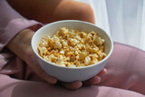 young women eating popcorn sitting on sofa at home 