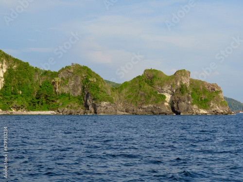 Rocky coast of a tropical island. View of the coast of the island covered with jungle and huge rocks near the water.