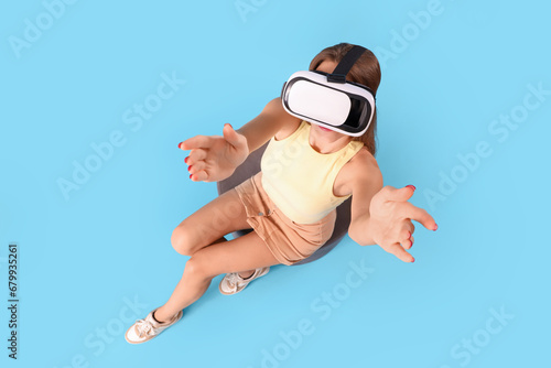Young woman using VR glasses on blue background, top view