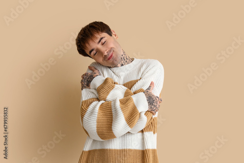 Young man hugging himself o...