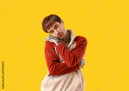 Young man hugging himself o...