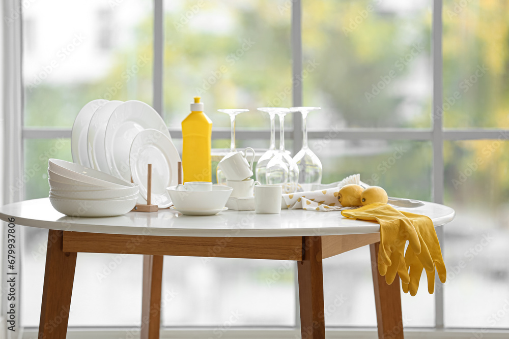 Set of white dishes with cleaning supplies and lemons on table in kitchen - obrazy, fototapety, plakaty 