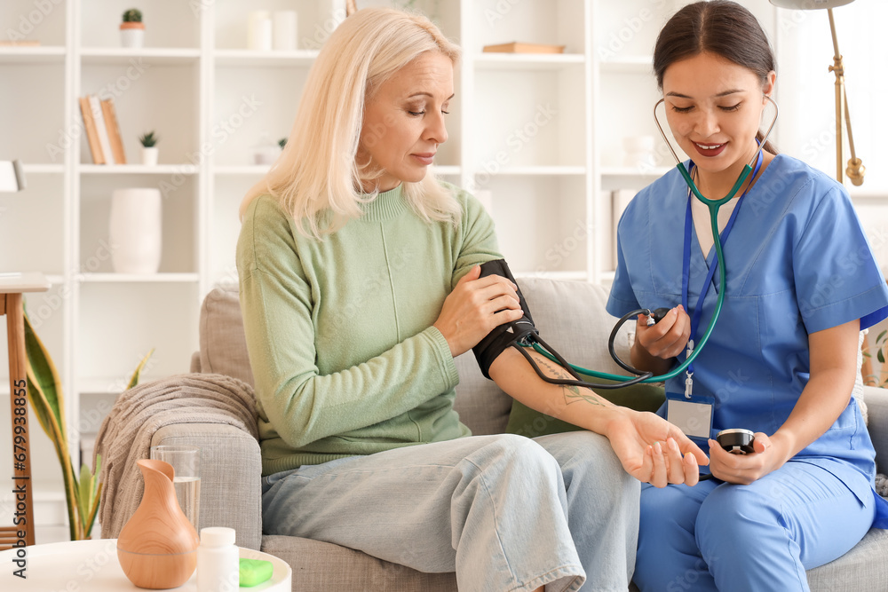 Female doctor measuring blood pressure of patient at home Female doctor measuring blood pressure of patient at home