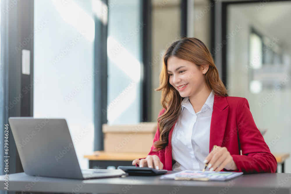 Young businesswoman using calculator and working with computer at office desk. Young businesswoman using calculator and working with computer at office desk.