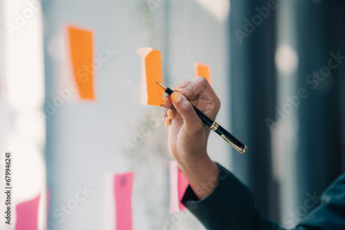 Close-up of hand Businesswoman writing sticky note to her mirror at the office. Business woman brainstorming and working and writing on the glass board in office. photo