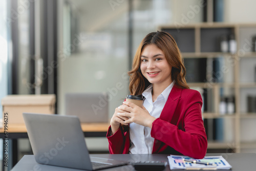 Successful businesswoman working and holding coffee cup at office. Confident businesswoman sitting happily in the office.