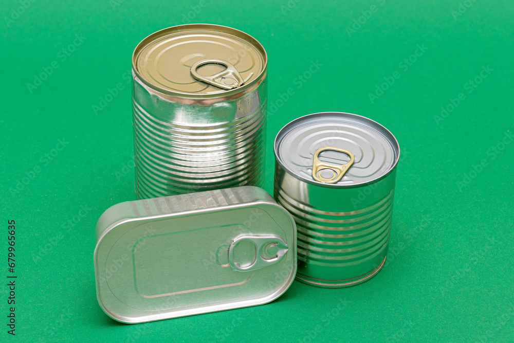 A Group of Stacked Tin Cans with Blank Edges on Green Background. Canned Food. Different Aluminum Cans for Safe and Long Term Storage of Food. Steel Sealed Food Storage Containers A Group of Stacked Tin Cans with Blank Edges on Green Background. Canned Food. Different Aluminum Cans for Safe and Long Term Storage of Food. Steel Sealed Food Storage Containers
