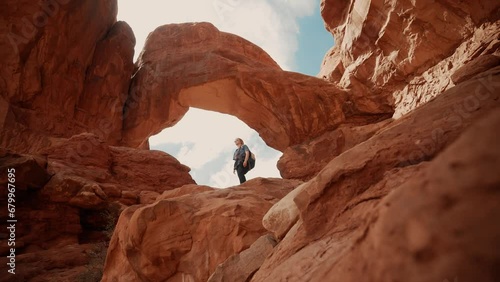 Female hiker looking around underneath beautiful natural canyon arches