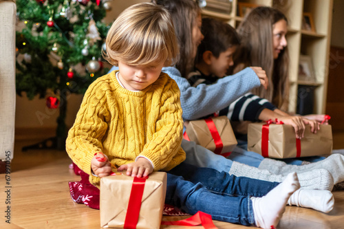 Beautiful 4-Year-Old Blond Boy Opening Christmas Gifts with Siblings