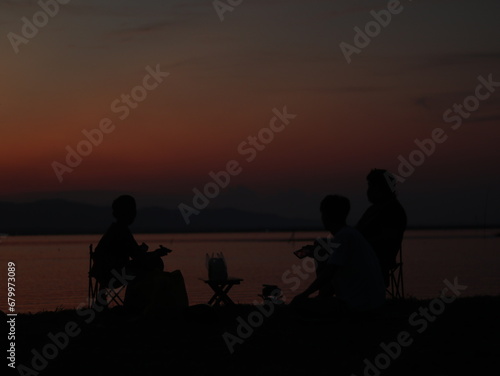 Silhouette of young men sitting by the lake enjoying the sunset. peaceful atmosphere in nature