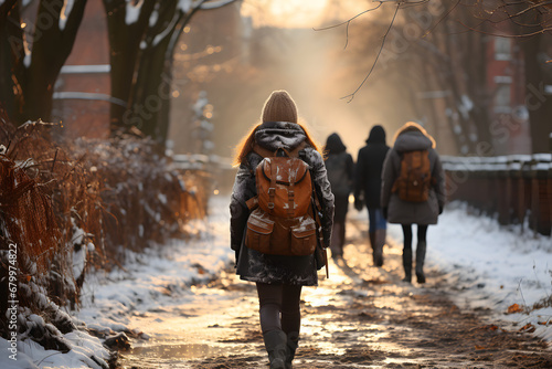 Back view of teenagers with backpack walking to school in winter photo