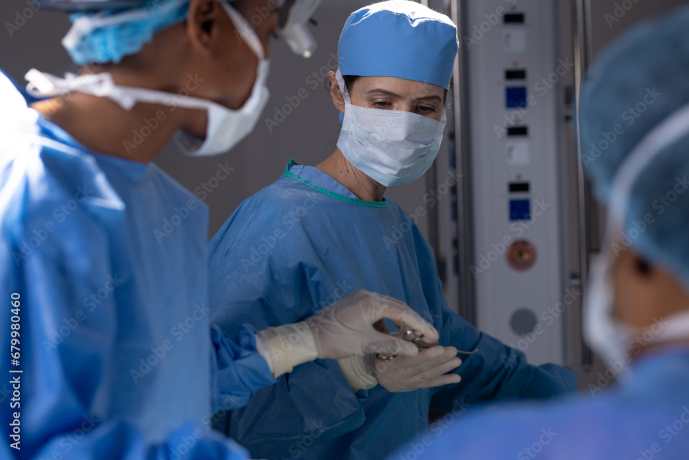 Diverse female doctors with face masks doing surgery in hospital operating room Diverse female doctors with face masks doing surgery in hospital operating room