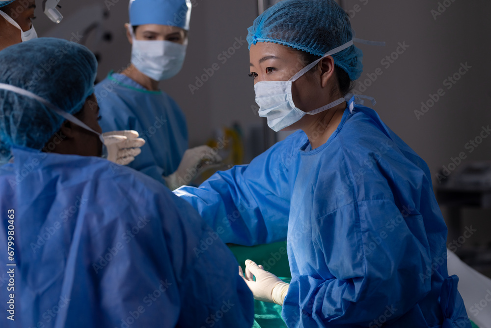 Diverse female doctors with face masks doing surgery in hospital operating room Diverse female doctors with face masks doing surgery in hospital operating room