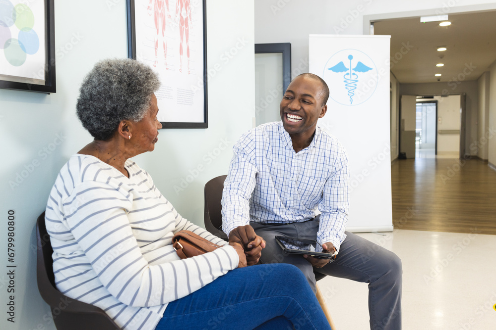 Happy african american male doctor using tablet and talking with senior woman in hospital Happy african american male doctor using tablet and talking with senior woman in hospital