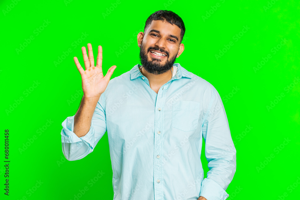 Young Indian man smiling friendly at camera, waving hands gesturing hello greeting or goodbye welcoming with invitation hospitable expression. Arabian guy isolated on green chroma key background Young Indian man smiling friendly at camera, waving hands gesturing hello greeting or goodbye welcoming with invitation hospitable expression. Arabian guy isolated on green chroma key background