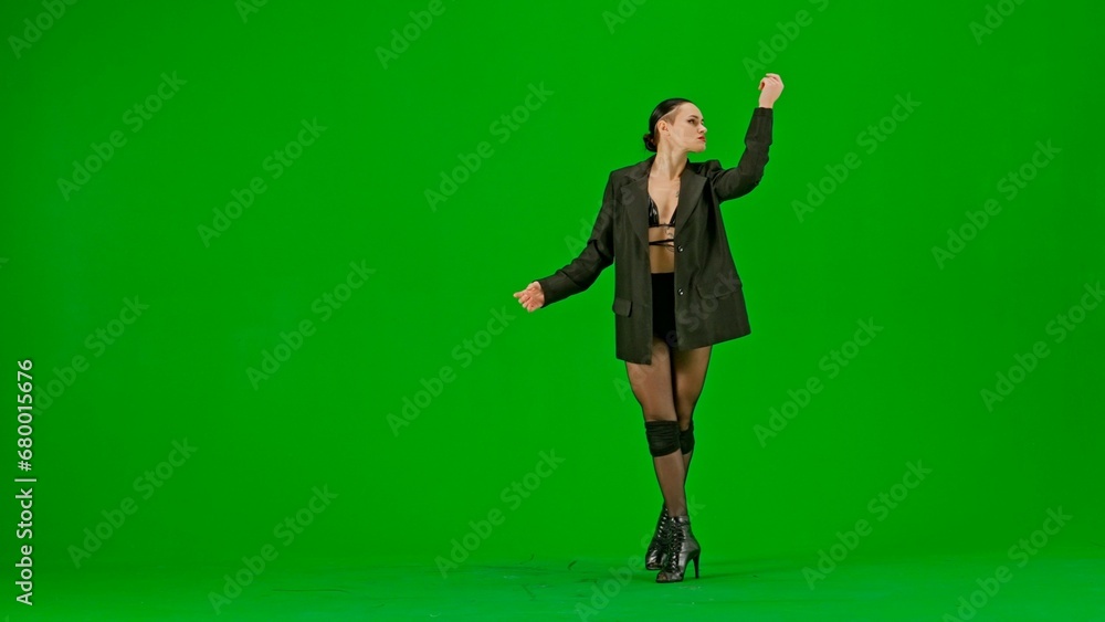 Framed on a green background, chromakey. Young woman wearing open clothing and jacket. Demonstrates a dance movement in the direction of high heels. She is sexy, plastic, rhythmic. Medium shot Framed on a green background, chromakey. Young woman wearing open clothing and jacket. Demonstrates a dance movement in the direction of high heels. She is sexy, plastic, rhythmic. Medium shot