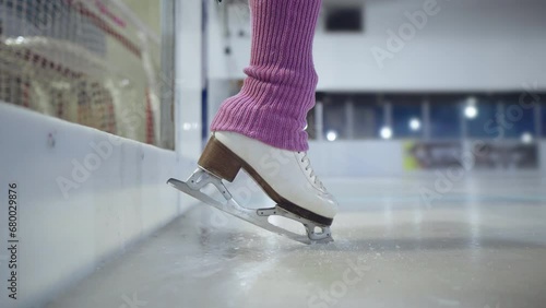 Figure Skater Skates Foot On Ice Entering The Ice Rink To Begin Her training wearing a pink leg warmers close up shot photo