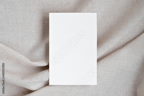 Blank white paper card mockup on neutral beige oat color crumpled linen fabric background with soft shadows, elegant boho wedding invitation or business branding template