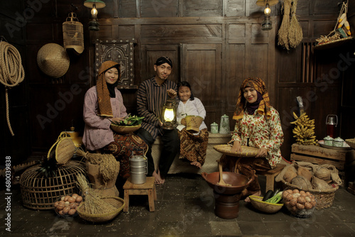 Portrait of Indonesian family wearing traditional clothes and sitting in the kitchen with happy expression photo