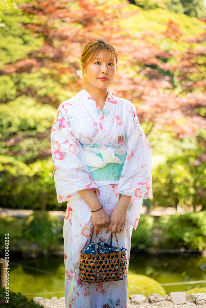 Portrait of a young woman wearing yukata summer kimono with soft blur background in a Japanese garden. Kyoto, Japan. Portrait of a young woman wearing yukata summer kimono with soft blur background in a Japanese garden. Kyoto, Japan.