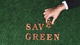 Hand arrange wooden alphabet in ECO awareness campaign design on biophilia green grass background to promote environmental protection for greener and sustainable future. Gyre