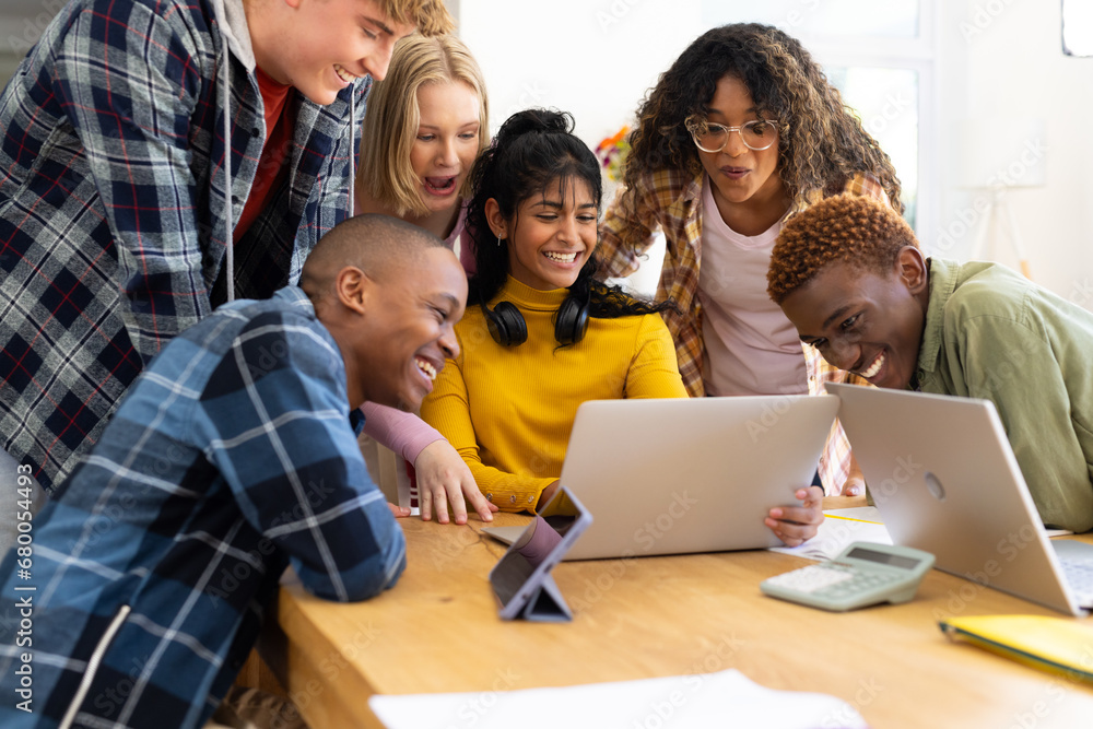 Happy diverse group of teenage friends studying with laptop and tablets at table at home Happy diverse group of teenage friends studying with laptop and tablets at table at home