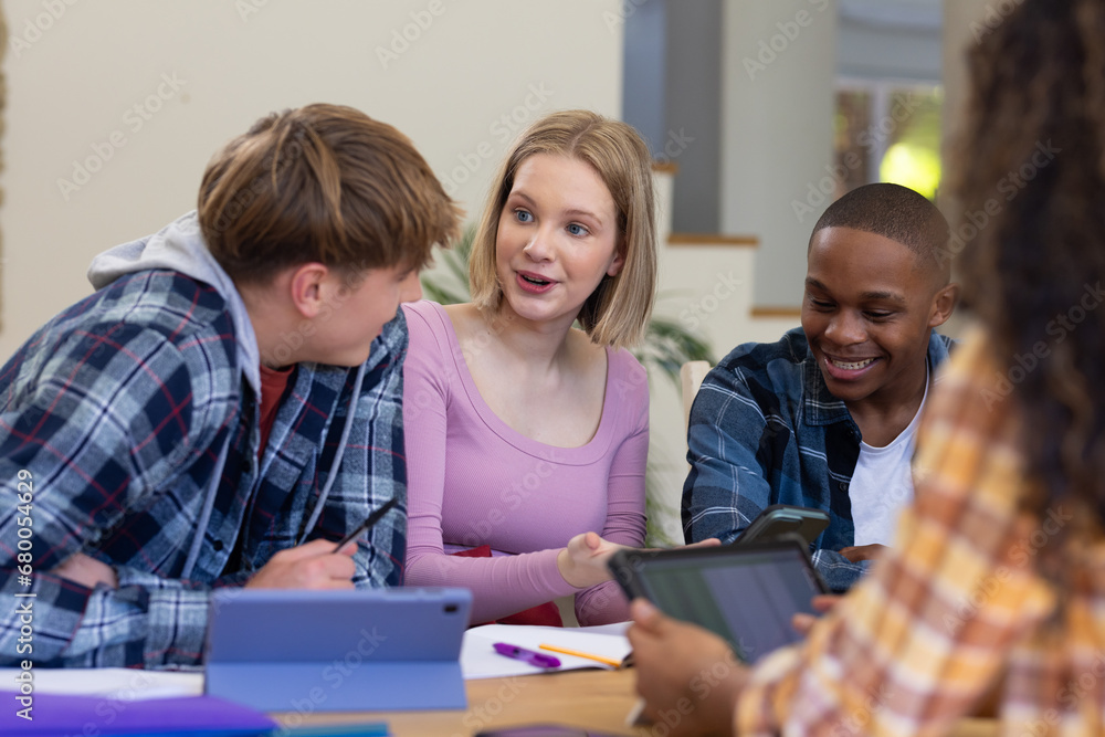 Happy diverse group of teenage friends studying with tablets at table at home Happy diverse group of teenage friends studying with tablets at table at home