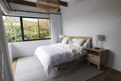 Big empty bedroom with white bed, wooden cabinet and big windows photo
