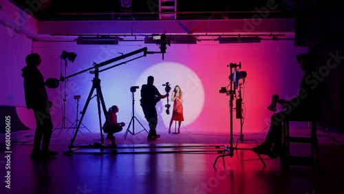Professional filming pavilion with a neon cyclorama. The process of preparing for the shooting of a music video. Director, Cameraman and crew in Backstage. photo