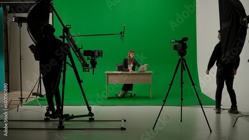 News anchor at work, woman journalist presenter telling breaking news, view of a backstage studio TV news shooting, chroma key template.