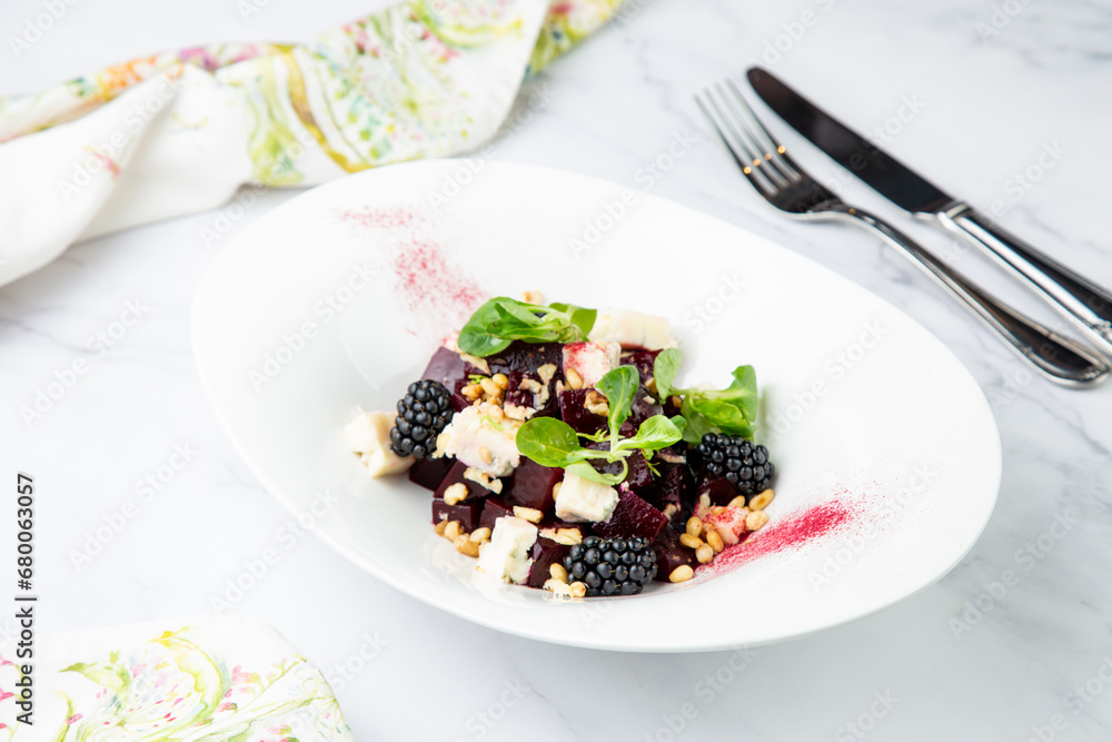 salad of blackberries, beets, seeds and cheese, side view on a white plate