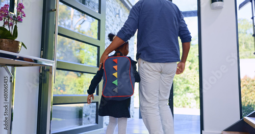 Father, child and back to school at door, walking in home and leave to start learning. Dad, kid and girl with backpack for first day, education or care, support of student with bag and hands together photo
