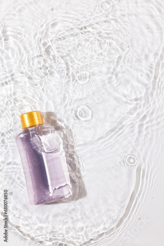 Vertical image of beauty product bottle in water with copy space background on white background