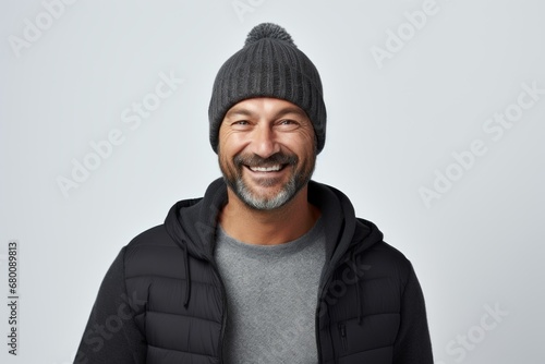 Portrait of a grinning man in his 40s donning a warm wool beanie against a white background. AI Generation