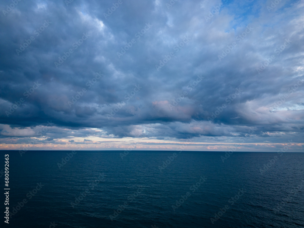 A bird's-eye view of a dark sea, horizon, and dramatic sky before a storm in the evening A bird's-eye view of a dark sea, horizon, and dramatic sky before a storm in the evening